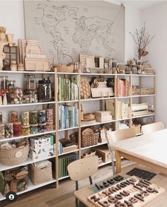 a room filled with lots of books and baskets on top of wooden shelves next to a whiteboard