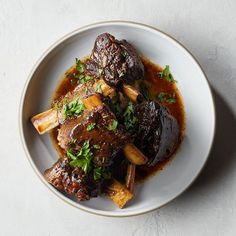 a white plate topped with meat covered in gravy and garnished with parsley