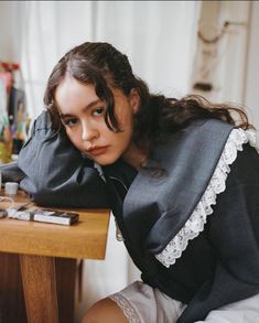 a woman sitting at a table with her hands on her head and looking off to the side