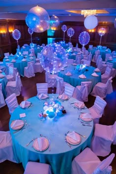 a room filled with lots of tables covered in blue cloths