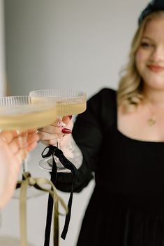 a woman holding up a glass of wine with a bow on the side and another person's hand reaching for it