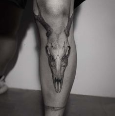 a black and white photo of a man's leg with an animal skull on it