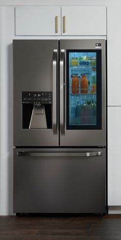 a stainless steel refrigerator with ice and water in it's door, on a wooden floor