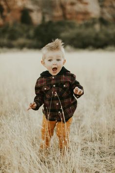 a young boy standing in tall grass with his mouth open