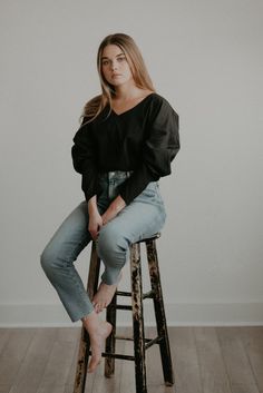 a woman sitting on top of a wooden stool