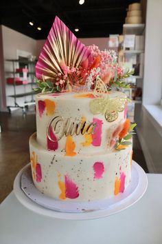 a three tiered cake with pink and orange flowers on it's side sitting on a table