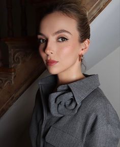 a woman in a gray coat is posing for the camera