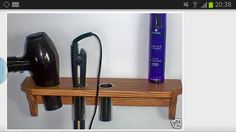 a hair dryer and blow dryer on a wooden shelf next to a wall