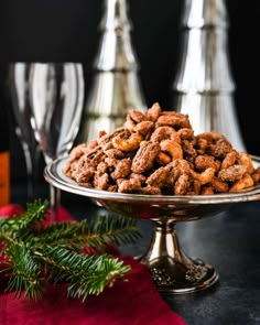 a plate full of nuts on a table next to two wine glasses and a red napkin