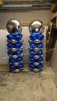 two shiny blue and silver balls sitting on top of each other in front of a wall