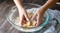 someone mixing ingredients in a glass bowl on top of a wooden table next to a towel