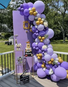 purple and gold balloons are hanging from the side of a tall column on a deck