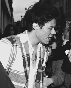 black and white photograph of a man eating food in front of a group of people