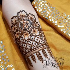 a woman's hand decorated with henna on her arm and legs, in gold sequins