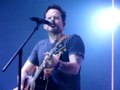 a man holding a guitar while standing in front of a microphone