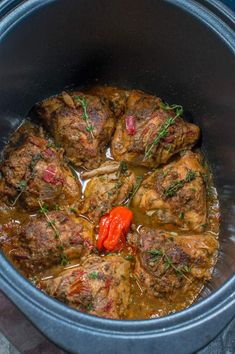 some meat and vegetables are cooking in a slow cooker with red peppers on the side