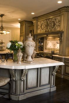 a large kitchen island with two vases on it and some flowers in the middle