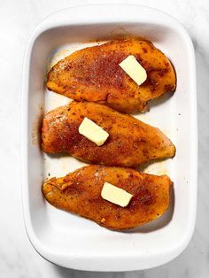 three pieces of chicken with butter in a white dish