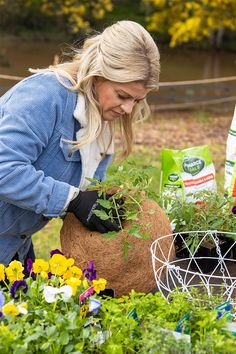 a woman is tending to some plants in a garden with other flowers and gardening supplies