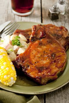 grilled pork chops, corn and potatoes on a plate