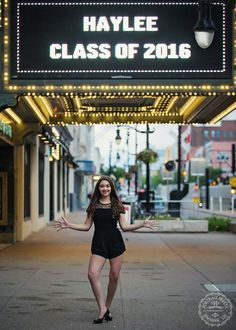 a woman posing in front of the haylie class of 2016 sign with her arms outstretched