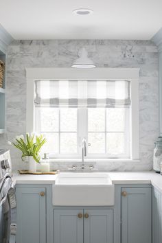 a white sink sitting under a window next to a washer and dryer in a kitchen