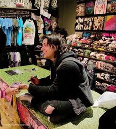 a man and woman sitting at a counter in a clothing store talking to each other