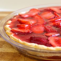 there is a pie with strawberries in it on the wooden table and ready to be eaten