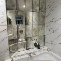 a white sink sitting under a bathroom mirror next to a wall mounted soap dispenser