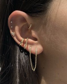 a woman's ear with two gold chains attached to the back of her ear