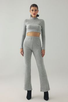 a woman in grey sweater and pants posing for the camera