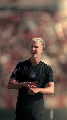 a man holding a red frisbee on top of a soccer field in front of a crowd