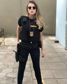 a woman in police gear standing on the sidewalk with her hand on her hip and looking at the camera