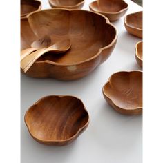 several wooden bowls with spoons in them on a white counter top and one is empty