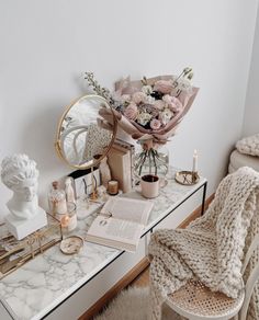 a white desk topped with a mirror next to a vase filled with flowers and candles