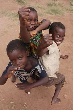 three young children posing for the camera with their hands in the air and one pointing at the camera