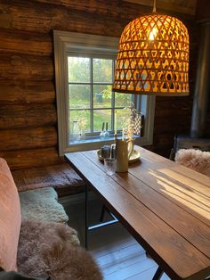 a wooden table sitting under a lamp next to a window