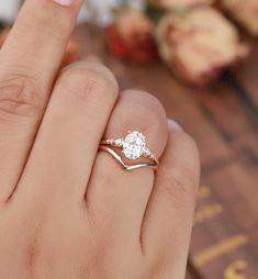 a woman's hand with a ring on her finger and an engagement ring in the other hand