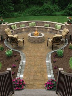 an outdoor fire pit surrounded by chairs and flowers