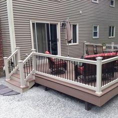 a deck with chairs and table next to a house