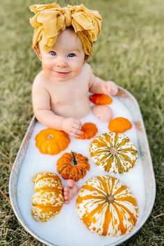 a baby sitting in a bathtub filled with pumpkins