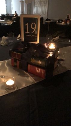 a table topped with books and candles on top of a black cloth covered tablecloth