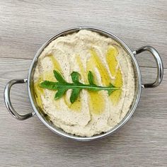 a metal bowl filled with hummus and lemons on top of a wooden table