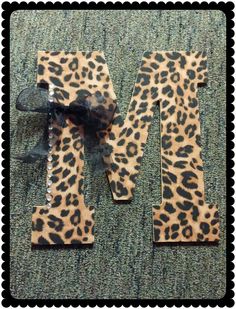 two pieces of animal print fabric tied to each other on a carpeted area with the letters m and n