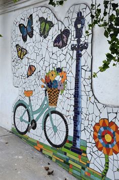 a mural on the side of a building depicting a bicycle with flowers and butterflies painted on it