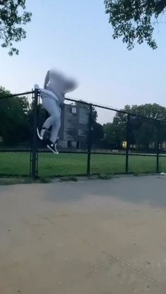 a person jumping in the air on a skateboard near a fence and grass area