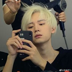 a man is getting his hair cut by another person with scissors and blow dryer