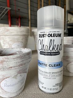 a close up of a bottle of paint next to some potted plants