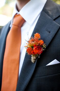 a man in a suit and tie with an orange boutonniere on his lapel