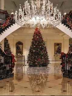 a christmas tree in the middle of a lobby with chandelier and staircases